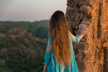 Back view of a girl in Pakistani dress viewing the green mountains 