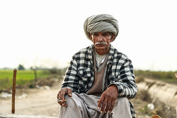 Old man in traditional clothes holding a half used cigarette