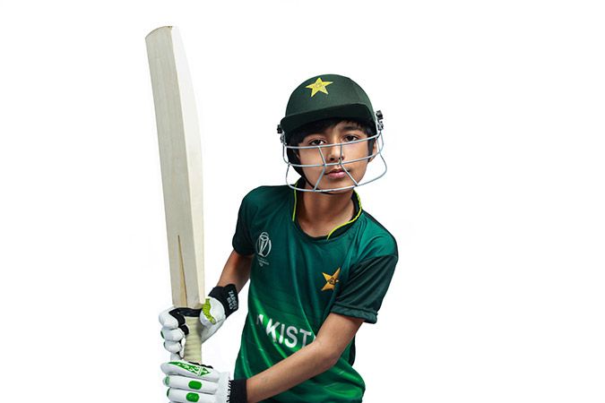 Kid playing cricket in pakistani kit