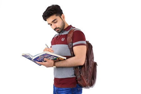 boy wearing a leather bag looking at book