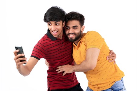 two friends hugging while looking at mobile screen