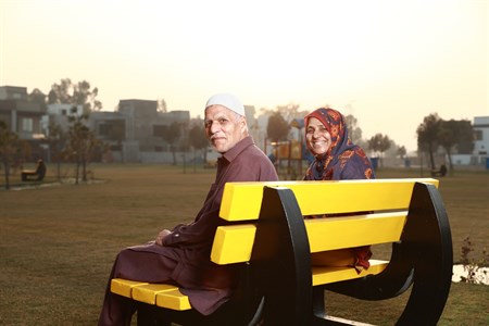 happy old couple sitting on a bench with smiling faces