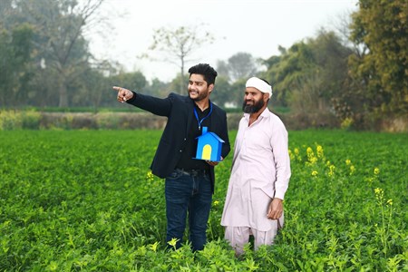 Banker holding a house prop in hand showing a beautiful future to farmer