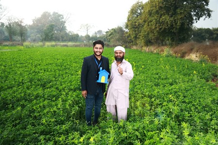Farmer giving a thumbs up while standing with a banker in the middle of fields