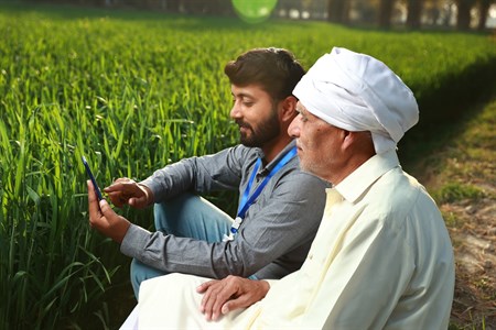 Banker showing farmer something on the mobile screen