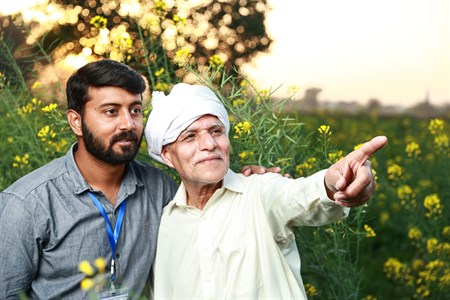 Banker standing with a farmer who is pointing in some direction