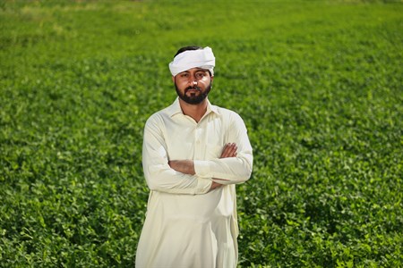 Man in traditional clothes with folded arms with fields as background