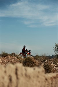 man wearing a helmet sitting on motorcycle at village/countryside