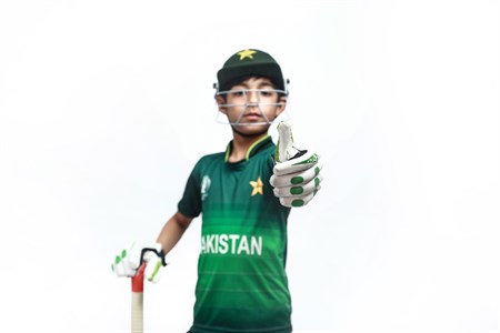 Kid giving thumbs up in pakistani cricket kit