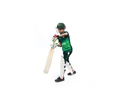 Kid playing cricket in pakistani kit
