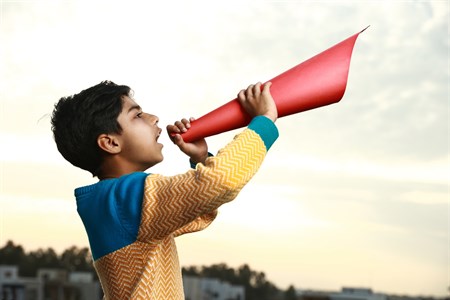 Kid holding a red paper speaker