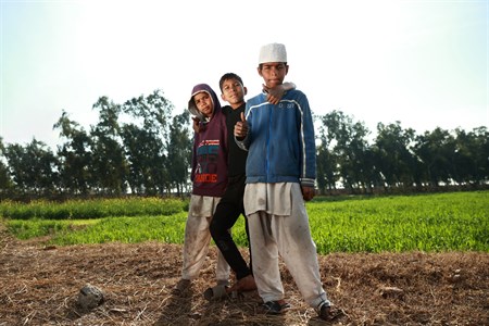 Three kids in different clothing style standing in the middle of fields