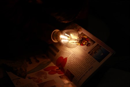 turned on filament bulb placed on open book page