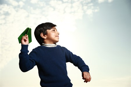 Kid about to throw a green paper plane in air