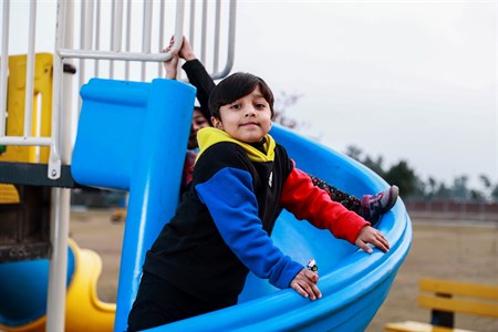 Kid on slide holding the side looking into camera