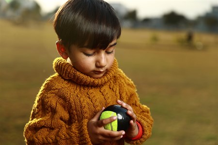 Kid holding and looking at tape tennis ball