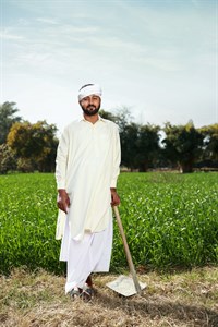 Farmer holding grape hoe standing in front of fields