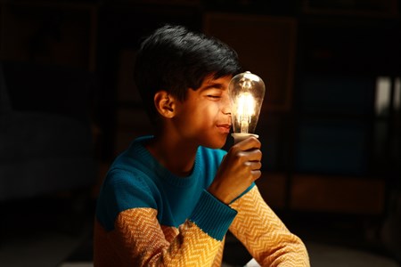Kid looking at a turned on bulb while holding it