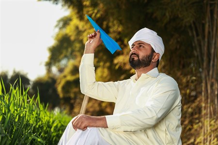 Man in traditional clothes holding a paper plane