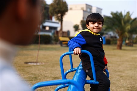 Kid smiling while holding one end of seesaw