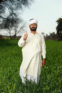 Man in traditional clothes giving thumbs up in front of fields