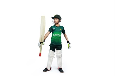 Kid showing bat in pakistani cricket kit