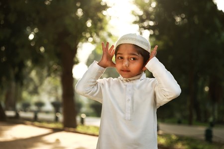 Kid posing the first posture of prayer with his hands up