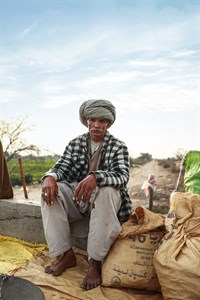 Man in traditional clothes sitting beside sacks