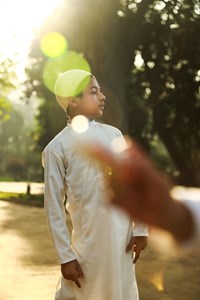 Kid wearing traditional clothes wearing muslim cap with lens flare