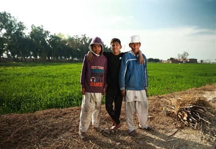 Three kids in different clothing style standing in the middle of fields