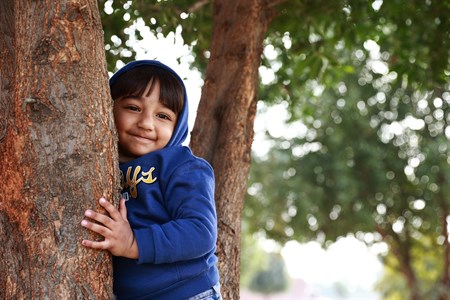 Smiling kid hugging a tree