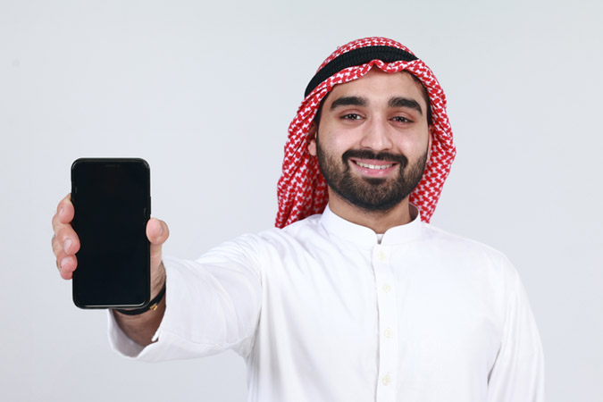 Arab casual man showing a mobile phone application isolated on a white background