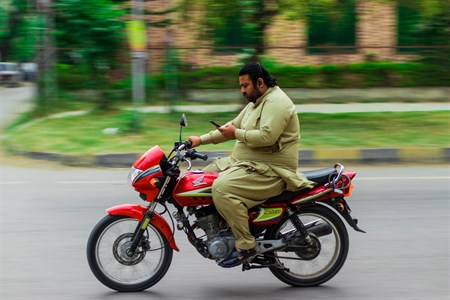 a man watching mobile phone on motorcycle without helmet