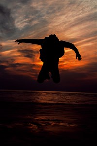 Silhouette of a boy jumping over sea sunset 